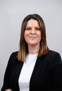 Porträtfoto einer Frau mit mittellangem Haar und weißem Oberteil.